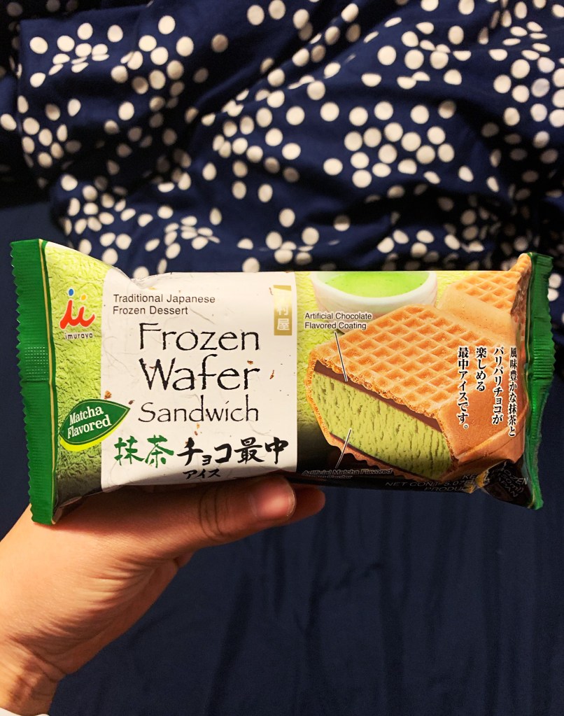 Ice cream sandwich held out by hand in front of black background